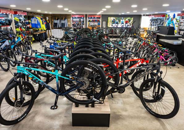 Another angle on the Plymstock showroom, hybrid and electric bikes mounted on the back wall, helmets and accessories on the shelf behind.